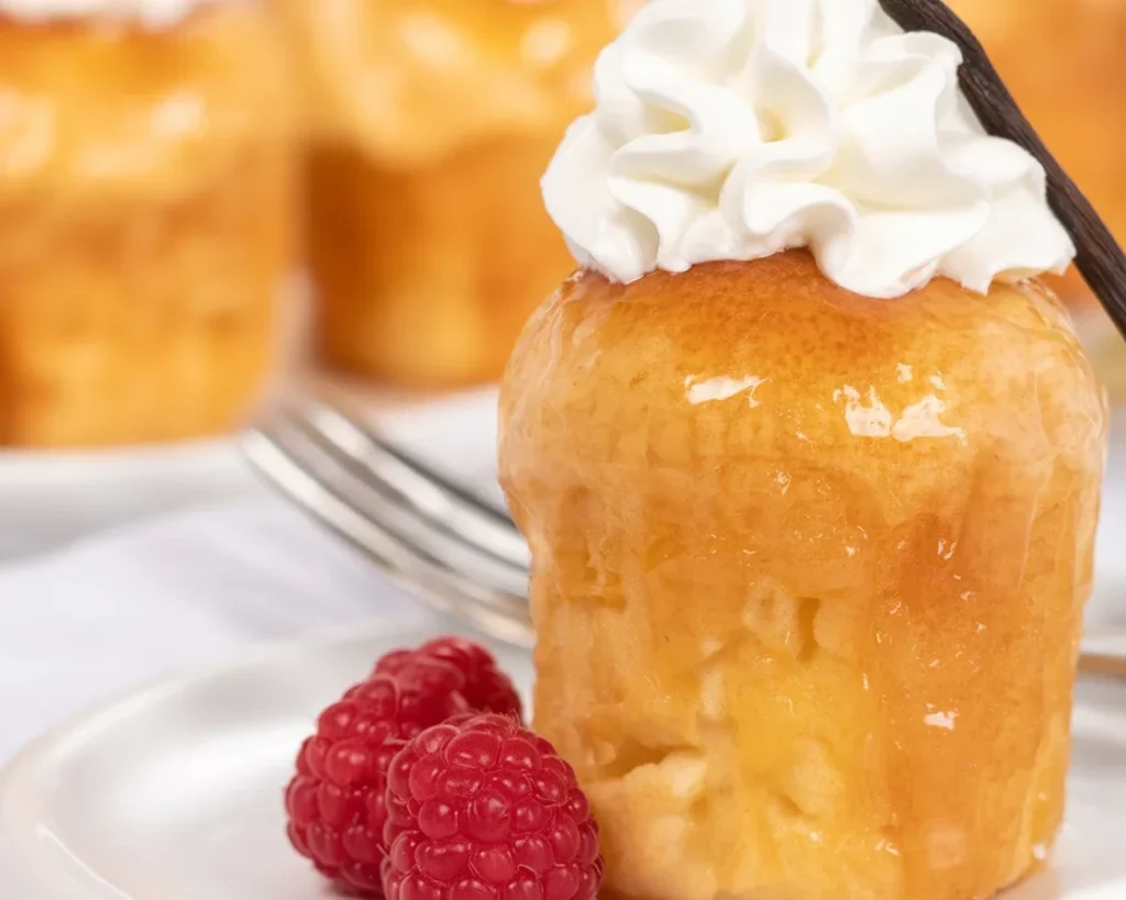 Un délicieux rum baba moelleux avec sirop de rhum, servi en portions individuelles.