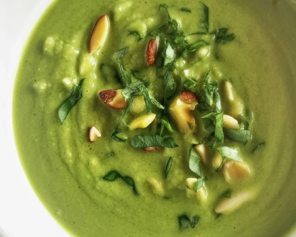 Soupe froide de petits pois et menthe servie dans un bol, garnie de glaçons à la menthe.